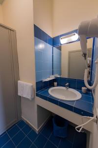 兰佩杜萨Hotel Baia Turchese的蓝色瓷砖浴室设有水槽和镜子