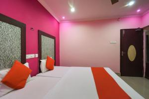 杜尔加布尔Hotel Kohinoor的一间卧室配有带粉色和橙色枕头的床