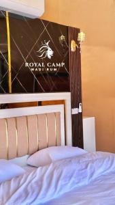 瓦迪拉姆ROYAl WADI RUM CAMP的卧室配有一张挂有墙上标志的床