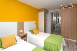 佩尼斯科拉安夸索公寓酒店的一间卧室设有两张床和黄色的墙壁