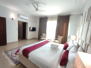 伊斯兰堡Margalla Hills Residency Islamabad Guest House的卧室配有带红色枕头的大型白色床