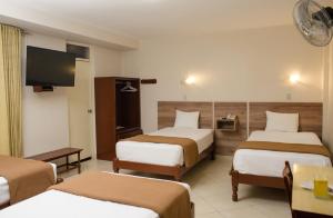 齐克拉约Hotel Santa Rosa的一间酒店客房,设有三张床和一台平面电视
