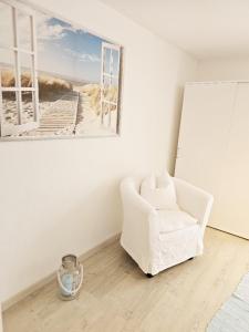 于伯林根Im Guggenbühl的一间设有白色椅子的房间,并展示了海滩的照片
