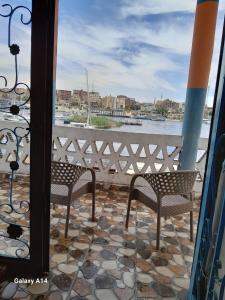 阿斯旺NiLe ViEW RANA NUbian Guest HOUES的阳台配有两把椅子,享有水景