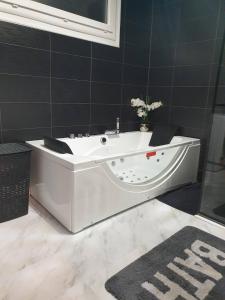 阿让Maison cosy au calme avec jardin的浴室铺有黑色瓷砖,配有白色浴缸。