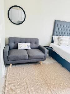 米德兰Gallagher Midrand BnB的一间卧室配有蓝色的沙发和镜子