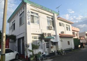 德之岛Guest House Minatoya Tokunoshima - Vacation STAY 01034v的前面有一辆汽车停放的白色建筑