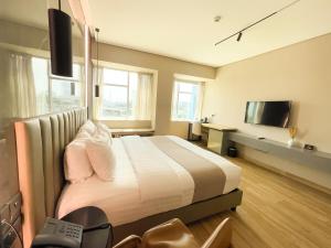 拉各斯Vertigo Hotel的一间卧室配有一张大床和电视