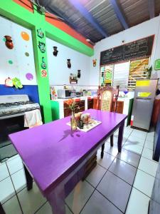 莱昂Hostal Leyendas的一张紫色桌子,放在厨房前,厨房配有一个柜台