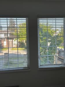 伯纳比Beautiful Home in Burnaby (Metrotown Area)的两个窗户,有百叶窗在房间