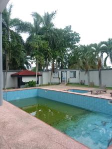 塔科拉迪DANGOTEC HOMES AND PROPERTIES的棕榈树建筑前的游泳池