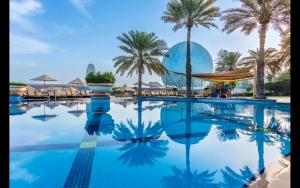 阿布扎比Al Raha Beach Hotel - Gulf View Room DBL - UAE的一座种有棕榈树和洋葱的大型游泳池