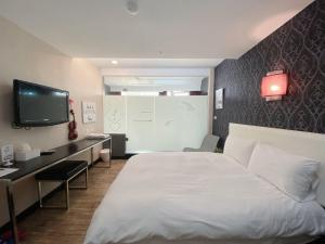 高雄日央商旅的酒店客房设有一张床、一张书桌和一台电视机。
