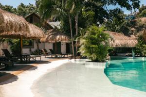莫阿尔博阿Secret paradise moalboal的度假村的游泳池配有茅草伞和椅子