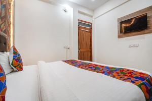 AyodhyaFabHotel Siya Bihari的卧室配有白色的床和色彩缤纷的毯子