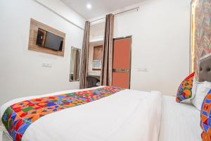 AyodhyaFabHotel Siya Bihari的卧室配有白色的床和色彩缤纷的毯子