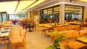 托尔博莱艾玛别墅旅馆的餐厅设有木桌、长凳和窗户。