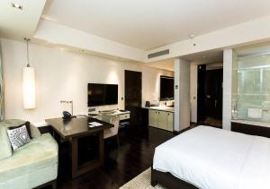 新德里The EL DE Belwood Hotel By Delhi Airport的酒店客房配有一张床、一张书桌和一台电视。