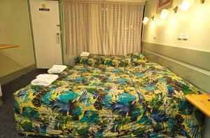 福布斯福布斯湖汽车旅馆的酒店客房,配有一张带色彩缤纷的被子的床