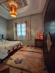马拉喀什DAR SARSAR airport的一间卧室配有一张床、地毯和吊灯