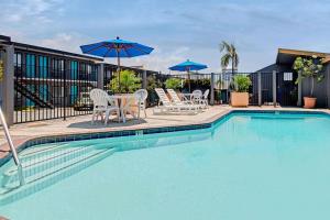 埃尔塞贡多Travelodge by Wyndham LAX的一个带桌椅和遮阳伞的游泳池