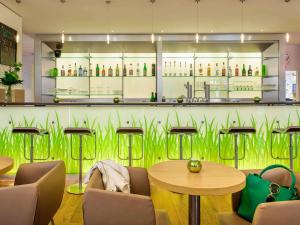 汉诺威宜必思酒店汉诺威医学园区 的餐厅设有绿色墙壁,配有桌椅