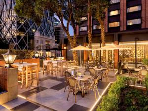 奥克兰Pullman Auckland Hotel & Apartments的室外餐厅设有桌椅和遮阳伞。