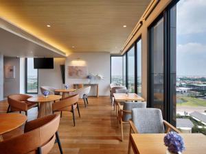 巴吞他尼Novotel Bangkok Future Park Rangsit的餐厅设有桌椅和大窗户。