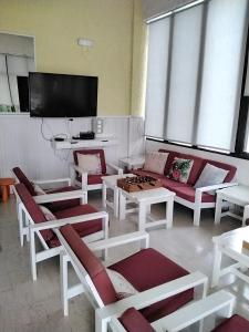 米尔托斯埃斯佩利兹酒店的客厅配有红色和白色家具以及平面电视。