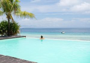 南威My Blue Hotel Zanzibar的一位在游泳池里看着大海的女人