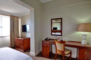 德班The Balmoral的酒店客房配有书桌、床和镜子