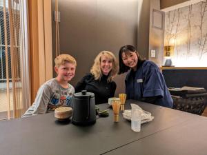 东京HOTEL TOMOS ASAKUSA的坐在桌子上的两名妇女和一名儿童
