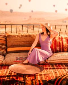 乌奇希萨尔Ages in Cappadocia的坐在沙发上的身着紫色连衣裙和帽子的女人
