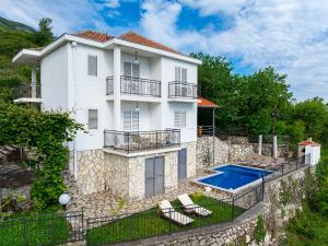布德瓦Villa Tranquila的白色的房子,设有游泳池和两把椅子