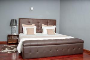 AbohijanaharyHôtel Les 12 Collines的一张大床,配有棕色皮革床头板和枕头