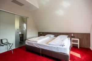 OverpeltHotel De Boskar Pelt的一间卧室配有一张大床,铺有红地毯