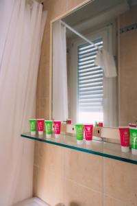 里米尼Hotel Enna Rimini的浴室的架子上装有绿和红杯