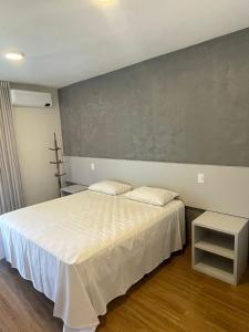 阿瓜斯迪林多亚Pousada Thermas das Montanhas的卧室配有白色的床和灰色的墙壁