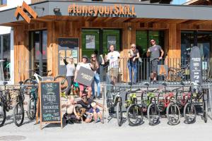 萨尔巴赫SKILL Mountain Lodge - Ski und Bike Hostel inklusive JOKER CARD的一群人站在一座建筑物前面,骑着自行车