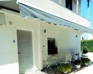伏罗拉villa Heljos apartaments的白色的建筑,设有门和桌椅