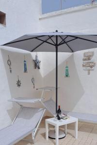 加利波利Cinque terrazze - Casa d'epoca con vista mare的一张带雨伞的白色桌子和一瓶葡萄酒