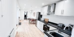 诺丁汉Single Room in Modern House near Nottingham的厨房铺有木地板,配有白色橱柜。