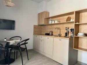 伊里斯斯Αura Luxury Apartments的厨房配有白色橱柜、桌子和用餐室。