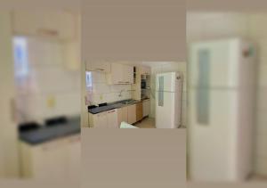 布卢梅瑙Casa aconchego em Blumenau的厨房配有白色橱柜和冰箱。