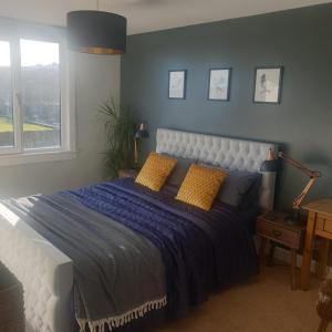特维德上游的贝里克Eastwatch guesthouse的一间卧室配有一张大床,配有蓝色的床单和黄色的枕头