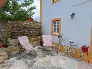 马夫拉Casa das Janelinhas - Cottage near Sintra, Mafra, Ericeira的两把椅子和一辆自行车停在大楼旁边