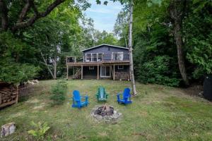 Oxtongue Lake3BR Rebecca Lakehouse with Fireplace Wifi and Dock的一座带蓝色椅子和火坑的房子