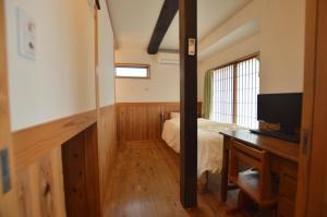 津市Guest House Ilonggo的一间卧室配有一张床和一张书桌及电视