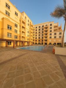 阿卜杜勒国王经济城Lotus Apartments的一座大型建筑,前面设有一个游泳池