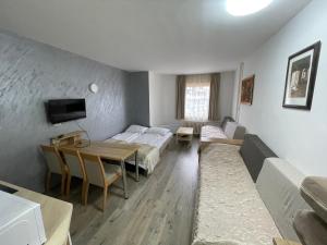科帕奥尼克Apartments Konaci Kopaonik的客房设有两张床、一张桌子和一张沙发。